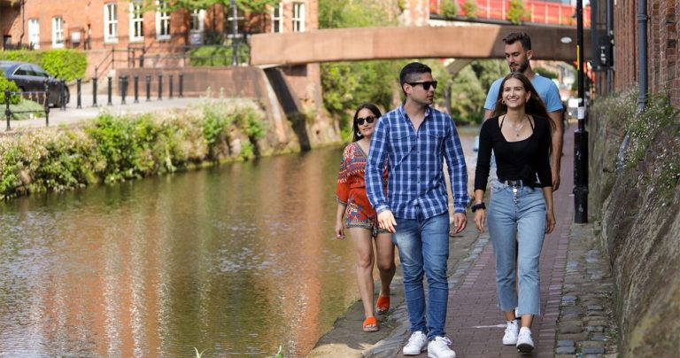 Students walking along the canal side in the sun