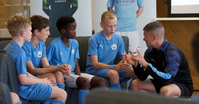 Manchester City Football coach training young players in class