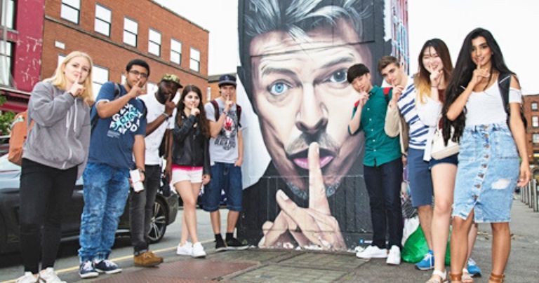 students posing in front of street art in manchester northern quarter