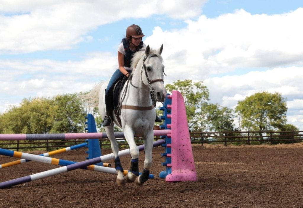 Girl jumping an obstacle on horseback during a horse riding lesson