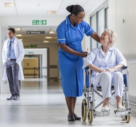 Nurse talking to patient in a wheelchair in a hospital corridor