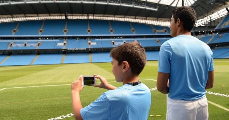 Boys taking pictures of the Etihad Stadium while on a tour
