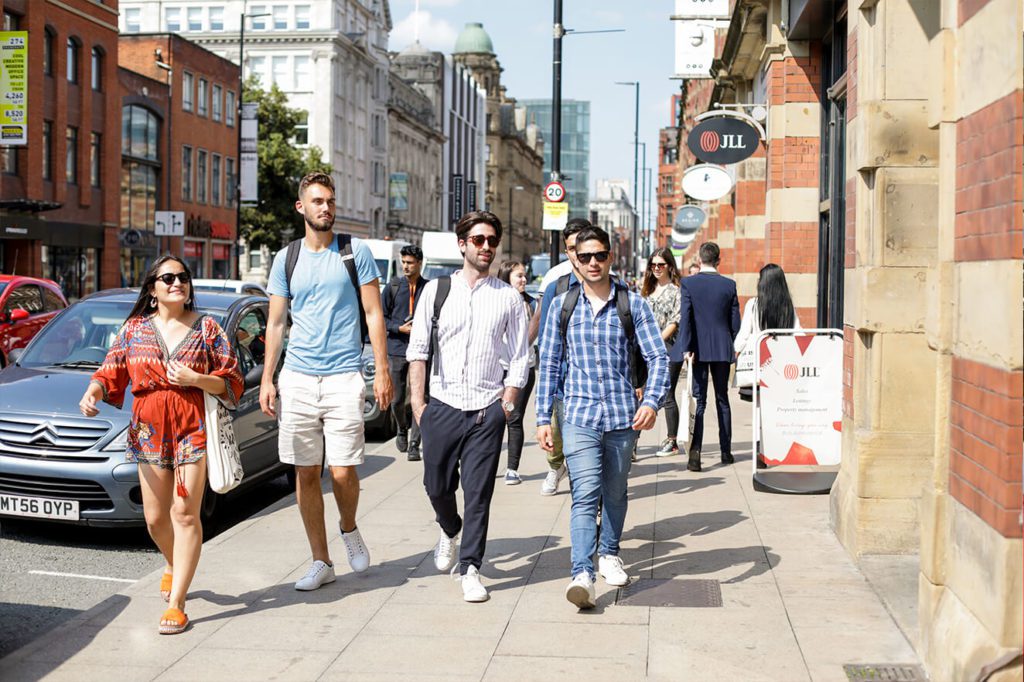 Students walking along a Manchester street in the sunshine
