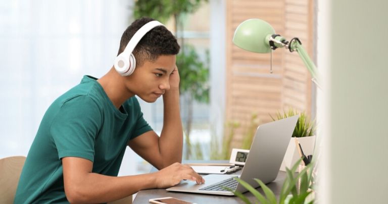 Boy in green t shirt with headphones at computer