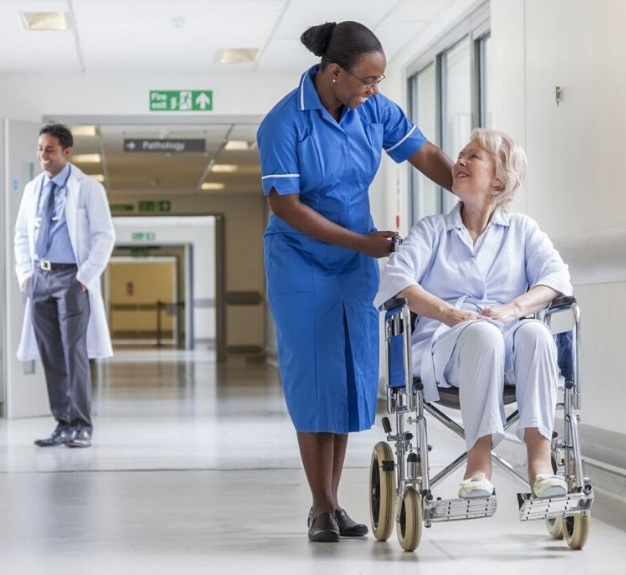 A nurse pushing an elderly woman in a wheelchair