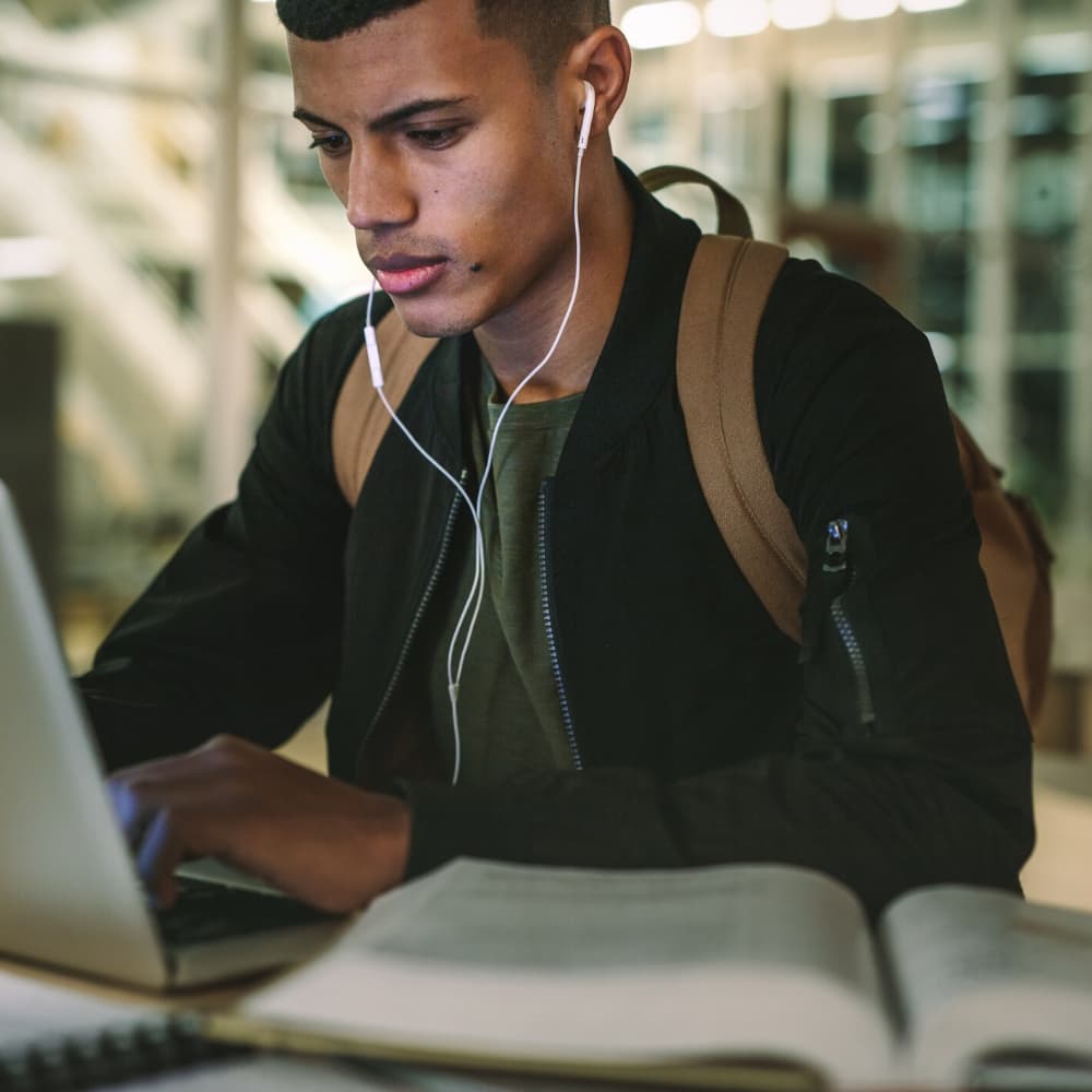 male university student listening to music and studying