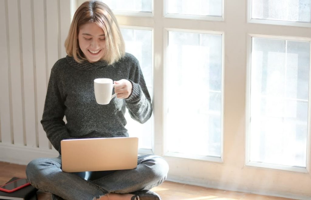 woman working online and drinking coffee while taking online CELTA course